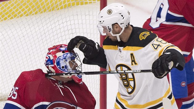 David Krej z Bostonu se pokou vyprostit svou hokejku, kter zashla montrealskho glmana Ala Montoyu.