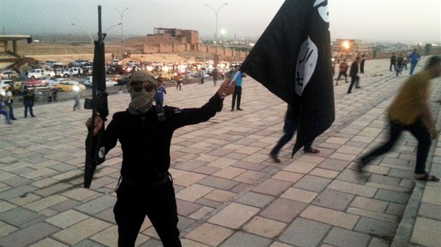 Bojovnk Islmskho sttu v Irku a Levant (ISIL) dr zbra a vlajku ISIL na ulici ve mst Mosul (23. ervna 2014).