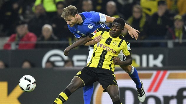 Dortmundsk Ousmane Dembele (ernolut) v souboji o m s Benediktem Hoewedesem z Schalke.