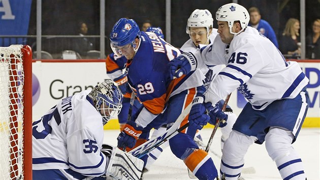 Roman Polk (vpravo) z Toronta od svho branke Jhonase Enrotha odtlauje Brocka Nelsona z NY Islanders.