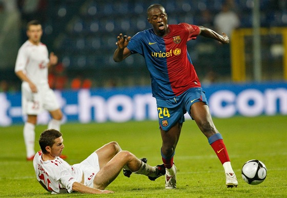 Leící Tomá Jirsák v dresu Wisly Krakov zastavuje Yayu Tourého z FC Barcelona.