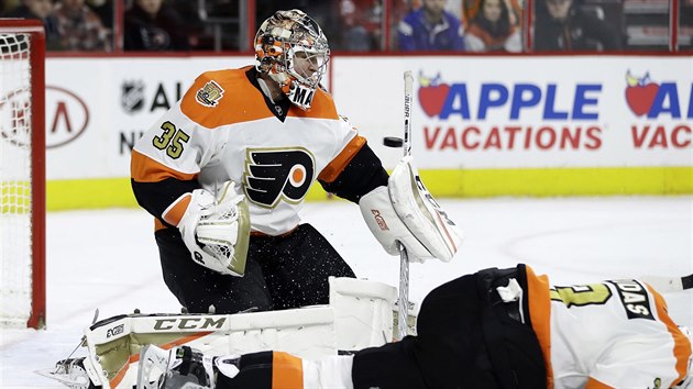 Brank Philadelphie Steve Mason se sna chytit puk, otesen Radko Gudas u mu nepome.