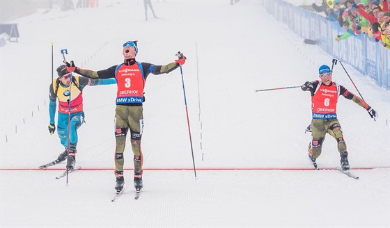 TSNÝ FINI. Simon Schempp projídí s rukama nad hlavou cílem hromadného závodu...