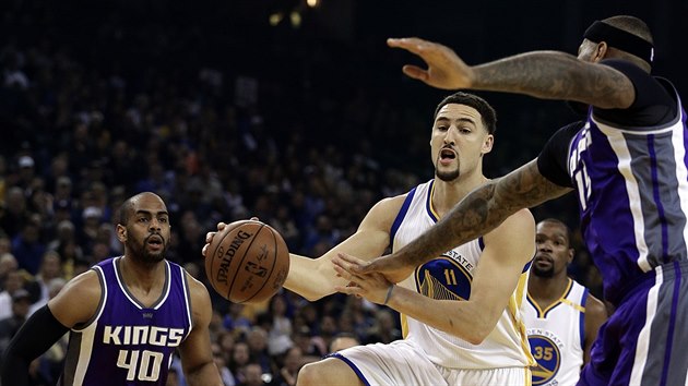 Klay Thompson (v blm) z Golden State se pokou prosmknout kolem Arrona Afflala (vlevo) a DeMarcuse Cousinse ze Sacramenta.