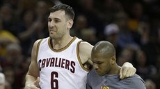 Andrew Bogut se belhá z palubovky, pomáhá mu James Jones.