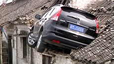 Po smyku skončilo SUV zapíchnuté ve střeše domu Po smyku skončilo SUV zapíchnuté ve střeše domu