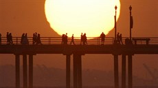 Lidé sledují západ slunce na molu v kalifornském Huntington Beach. (29. kvtna...