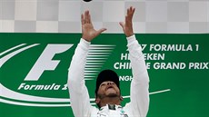 HOP. Lewis Hamilton si hraje s trofejí pro vítze Vellké ceny íny.