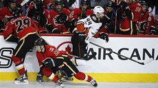 Nate Thompson z Anaheimu prchá dvojici Deryk Engelland, Johnny Gaudreau z...