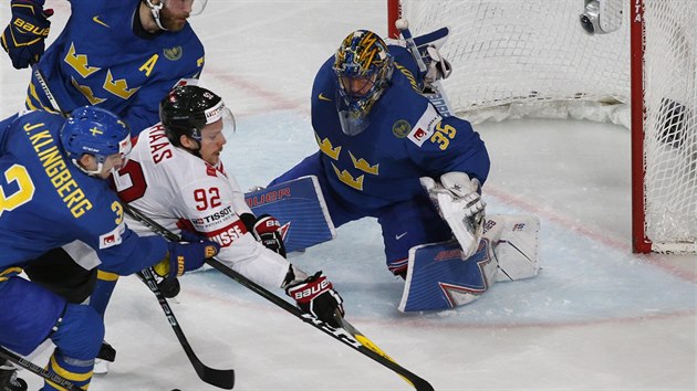 vcar Getan Haas (v blm) se dere vdskou obranou - na zdech si veze Johna Klinberga - k volnmu kotoui. Ve kontroluje glman Henrik Lundqvist.