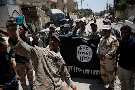 Irátí vojáci se fotí s ukoistnou vlajkou Islámského státu v osvobozené ásti Mosulu