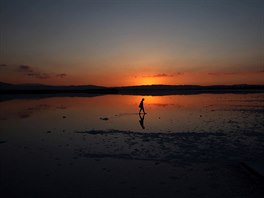 A tourist walks during the sunset at a salt lake in Larnaca