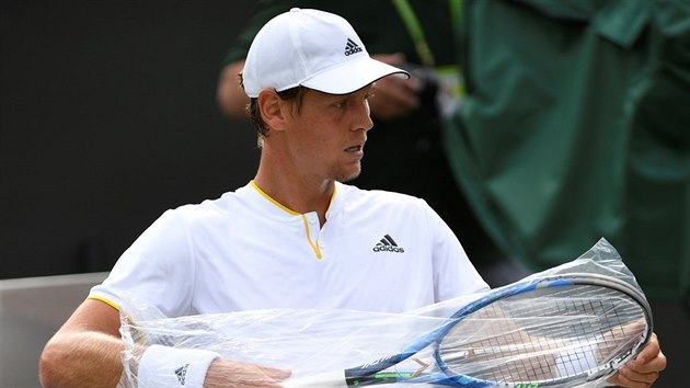 Tom Berdych si vybaluje novou raketu v osmifinle Wimbledonu.