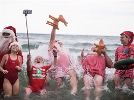 LETNÍ VÁNOCE. Lidé pevleení za Santa Clause se koupou v moi pi Svtovém...