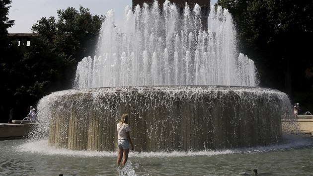 Turistka se chlad ve fontn ped hradem Sforzesco v Miln (1. srpna 2017)