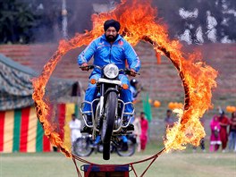 OHNIVÁ OBRU. Indický policista na motorce proskakuje zapálenou obruí bhem...