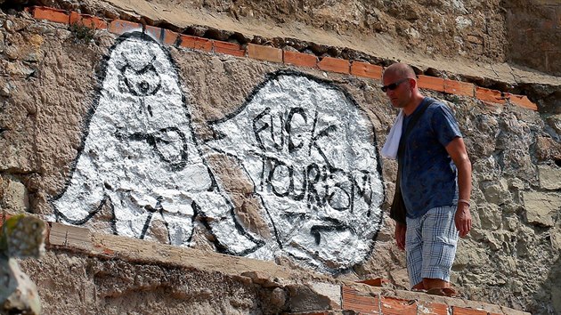 Mu prochz kolem protituristickho graffiti na zdi starho bunkru v barcelonsk tvrti Carmel (3. srpna 2017)