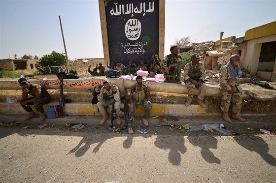 Vojáci íitské jednotky sedí vedle vlajky Islámského státu poté, co spolu s...