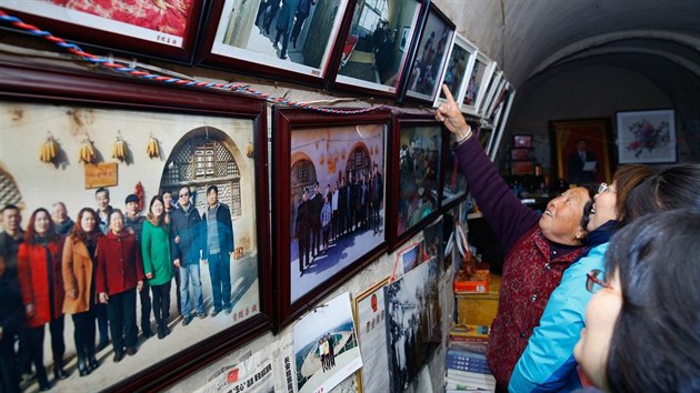 This picture taken on October 22, 2016 shows people looking at photos of Chinese President Xi Jinping at a cave home where Xi lived as a youth, in Liangjiahe, in China's Shaanxi province. Three caves in a remote Chinese village where Xi Jinping was sent during the Cultural Revolution receive a constant stream of Communist pilgrims, come to pay homage four years after he came to power.