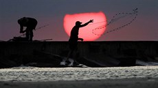 VÝCHOD SLUNCE. Rybář rozhazuje sítě při sobotním východu slunce v Port Aransas... VÝCHOD SLUNCE. Rybář rozhazuje sítě při sobotním východu slunce v Port Aransas...