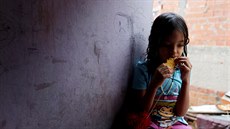 Malá obyvatelka slumu v Caracasu jí placku zvanou arepa. (21. srpna 2017)