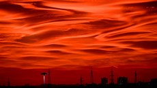 OHNIVÁ ZÁŘE. Siluety sloupů elektrického vedení a budov kontrastují s ohnivě... OHNIVÁ ZÁŘE. Siluety sloupů elektrického vedení a budov kontrastují s ohnivě...