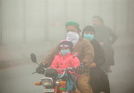 Lidé projídí pákistánským mstem Lahora, který trápí smog.