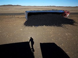A photographer casts his shadow near a coal truck which flipped over at...