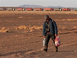 A man carries groceries to men who are digging their coal truck out of the...