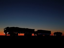 Trucks carrying coal are seen on the road as darkness descends on the route to...