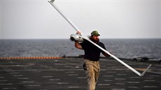 Námořník nese na rameni bezpilotní stroj ScanEagle amerického letectva. Váží... Námořník nese na rameni bezpilotní stroj ScanEagle amerického letectva. Váží...
