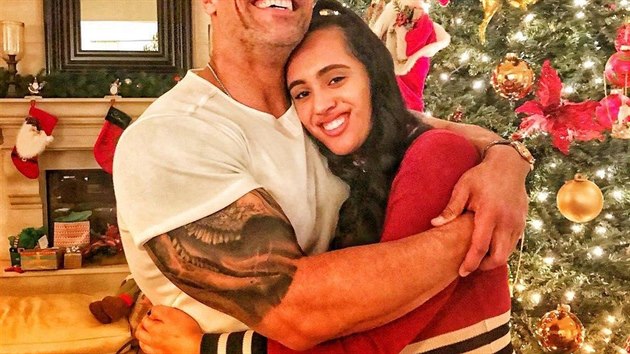 Dwayne Johnson známý také jako Rock se svou nejstarší dcerou Simone před klasickým stromkem v tónech zlaté a červené.