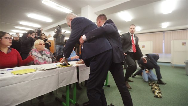 Polonah ena s npisem v anglitin, e Zeman je Putinova dvka, bela ve volebn mstnosti k prezidentovi a kiela na nj. Proti en zakroila Zemanova ochranka a zrove prezidenta odvedla z volebn mstnosti. (12. ledna 2018)
