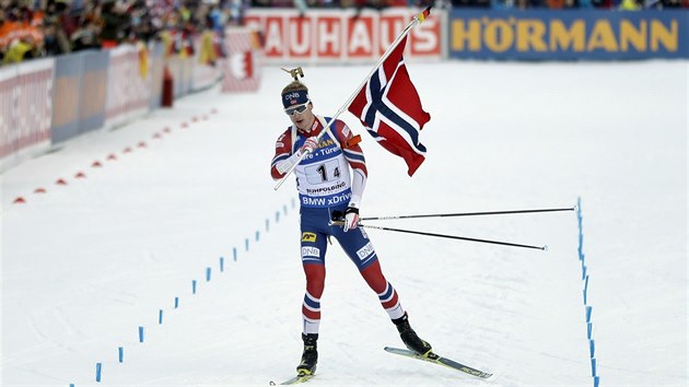 S VLAJKOU ZA DALŠÍM TRIUMFEM. Johannes Thingnes Bö projíždí cílem štafety v Ruhpoldingu na prvním místě.
