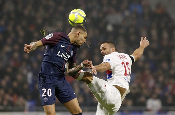 Layvin Kurzawa z PSG (v modrém) hlavikuje, zatímco do nj koupe soupe z Lyonu...