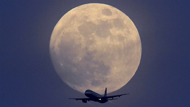 MSÍC NAD LONDÝNEM. Letadlo British Airways se vznáí nad Londýnem na nebi s...