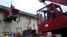 Hasiči jeřábem zvedli k oknu přípojný vozík za auto. Pacienta přeložili na... Hasiči jeřábem zvedli k oknu přípojný vozík za auto. Pacienta přeložili na...