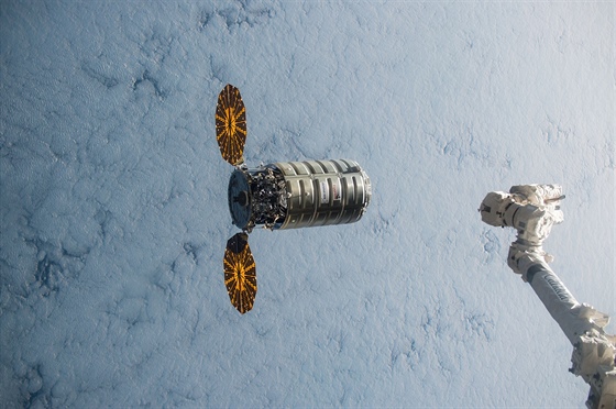 Kosmický náklaák Cygnus u stanice ISS, vpravo je robotické rameno Canadarm2.