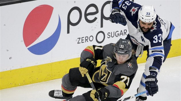 William Karlsson z tmu Vegas Golden Knights a Dustin Byfuglien z  Winnipegu v souboji o puk.