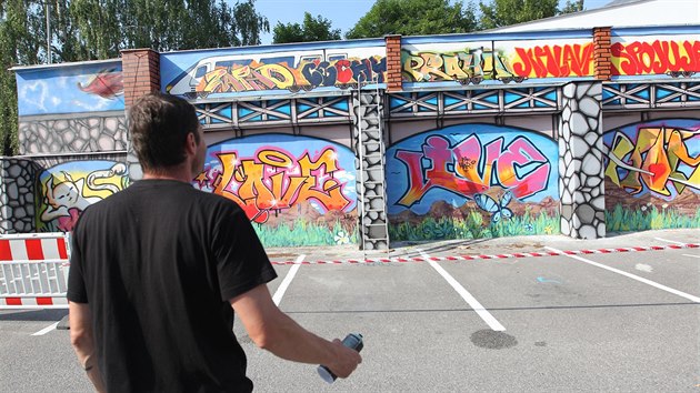 Jakub Menk dokonuje ob graffiti na zdi v jihlavsk Bezruov ulici. S prac mu obas pomhaj ptel.