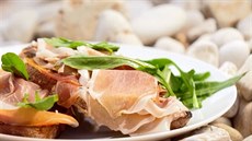 Topinka s česnekem, rajčaty a španělskou šunkou připravená na grilu Topinka s česnekem, rajčaty a španělskou šunkou připravená na grilu
