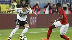 Nmecký fotbalista Mesut Özil klikuje ped rakouským Davidem Alabou