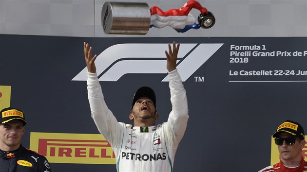 Lewis Hamilton (uprosted) si na pdiu pohazuje s trofej pro vtze Velk ceny Francie.
