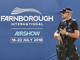 An armed police officer stands guard at Farnborough International Airshow in...