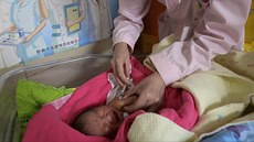 In this April 25, 2017, photo, a baby receives a vaccine shot next to a poster... In this April 25, 2017, photo, a baby receives a vaccine shot next to a poster...