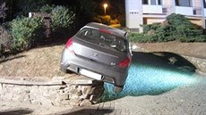 Řidička si při couvání nevšimla, kam jede. Auto vzpříčila na zídce. Řidička si při couvání nevšimla, kam jede. Auto vzpříčila na zídce.