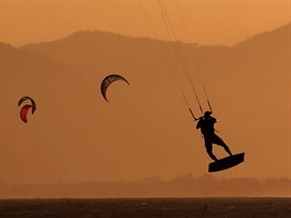 VEERNÍ JÍZDA. Kitesurfai brázdí vlny na plái Barra da Tijuca v brazilském...