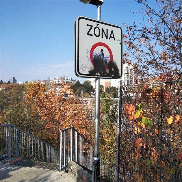 Dobrý den, značka je umístěna na cestě z Kačerova přes železniční trať nad schody vedoucí k autobusovým garážím Kačerov.