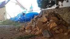 V historických hradbách je asi deset metrů široká díra. Za ní jsou stále na... V historických hradbách je asi deset metrů široká díra. Za ní jsou stále na...