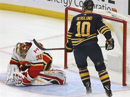 Brankář David Rittich z Calgary kryje puk před Patrikem Berglundem z Buffala.